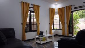 sala de estar con cortinas amarillas y mesa con ordenador portátil. en Villa 165 Puncak en Cisarua