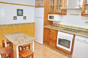 een keuken met houten kasten en een witte koelkast bij Apartamento Acuario in Conil de la Frontera