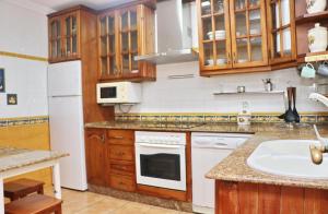 cocina con armarios de madera y fregadero blanco en Apartamento Acuario, en Conil de la Frontera