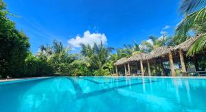 a swimming pool with blue water and palm trees at ITALIAN GUEST in Trincomalee