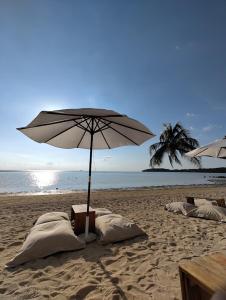 a beach with an umbrella and pillows on the sand at Jayden Villas in Hinkong