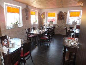 um restaurante com mesas e cadeiras de madeira e janelas em Pension Seiboldsmühle em Heideck