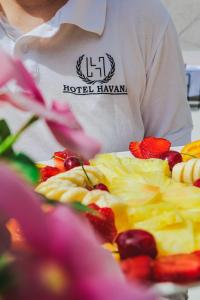 un hombre está de pie junto a un plato de fruta en Hotel Havana, en Sarandë