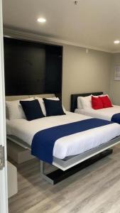 a bedroom with two beds with blue and red pillows at Omeo Suites in Alhambra