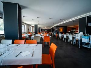 a dining room with white tables and orange chairs at Apartamentos La Solana in Pla de l'Ermita