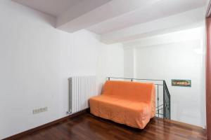uma cama laranja num quarto branco com pisos em madeira em La belle époque di Assisi 1 em Assis