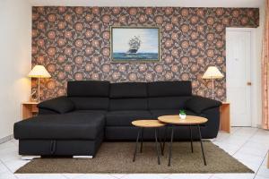 a living room with a black couch and a table at Apartman Brigitte Bükfürdő in Bük