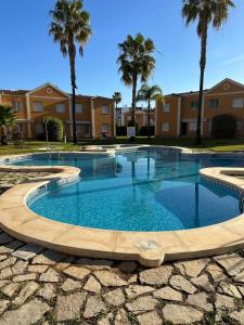 uma grande piscina num quintal com palmeiras em OLIVA NOVA GOLF BEACH & RESORT club sevilla IV 2A em Oliva