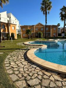 a swimming pool in a yard with palm trees and buildings at OLIVA NOVA GOLF BEACH & RESORT club sevilla IV 2A in Oliva