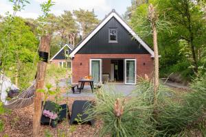 ein kleines rotes Backsteinhaus mit schwarzem Dach in der Unterkunft Luxe Vakantiehuis Huismus Veluwe in Nunspeet