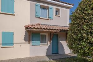 ein Haus mit blauen Fensterläden und einer Hecke in der Unterkunft Maison à 500m de la plage pour 4 in Saint-Brévin-lʼOcéan