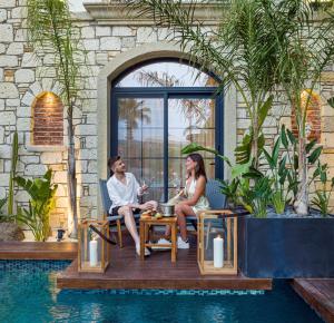 a man and woman sitting around a table next to a pool at Dmira Alacati in Alaçatı