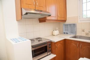 a kitchen with wooden cabinets and a stove top oven at Kapetanios Apartments in Agios Stefanos