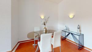 a dining room with a glass table and white chairs at Apartamento T1 Albufeira Golden 101 in Albufeira
