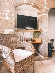 sala de estar con silla de mimbre y TV en Mon Petit Coin de Paradis, en Golinhac