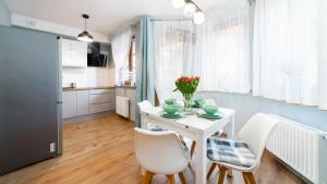een keuken en eetkamer met een witte tafel en stoelen bij Apartament Szept Lasu - z prywatnym parkingiem - Space Apart in Karpacz