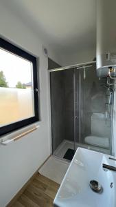 łazienka z prysznicem, umywalką i oknem w obiekcie W Kręgu Natury 