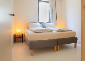 een bed in een kamer met een raam bij Zilt aan Zee in Egmond aan Zee