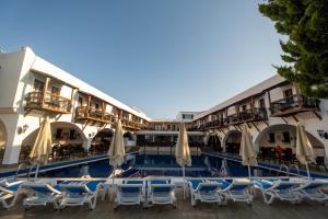 a hotel with a pool with chairs and umbrellas at Costa Bitezhan Hotel - All Inclusive in Bitez