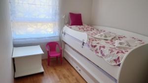 1 dormitorio pequeño con 1 cama con silla rosa en Apartment Summerhill, en Primošten