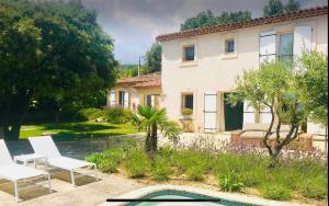 a house with two white chairs and a swimming pool at Stramousse in Cabris