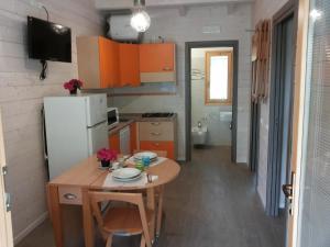 a small kitchen with a table and a refrigerator at Villaggio Samoa in Lido delle Nazioni