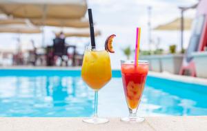 two drinks sitting on a table next to a pool at Hotel Oaz in Golem