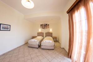 1 dormitorio con 2 camas y ventana en Kapetanios Apartments, en Agios Stefanos