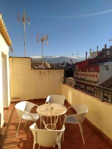 patio con mesa y sillas en el balcón en Hostal El Olivo, en Granada