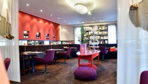 un restaurant avec des chaises violettes et un mur rouge dans l'établissement Villa Mittermeier, Hotellerie & Restaurant, à Rothenburg ob der Tauber