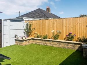 a backyard with a fence and green grass at The Bay Cottage in Thornton