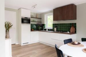 une cuisine avec des armoires blanches et une table dans l'établissement Luxe Vakantiehuis Ruwe Iep Veluwe, à Nunspeet 35 autres photos