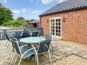 a patio with a table and chairs in front of a brick building at Manor Farm Retreat in Hainford