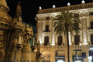 um edifício com uma estátua e uma palmeira em frente em Palazzo Moncada appartamento 2 em Palermo