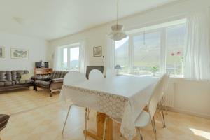 Sea and Mountain View - Scenic Village - 2BR House في Viðareiði: غرفة طعام مع طاولة بيضاء وكراسي