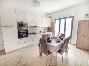 une cuisine blanche avec une table et des chaises et une cuisine avec des placards blancs dans l'établissement Appartamento Alighieri primissima fila mare, à Martinsicuro