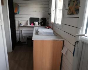 - une cuisine avec évier dans une petite maison dans l'établissement petite maison 15 mn à pied du marche et vieux port, à La Rochelle