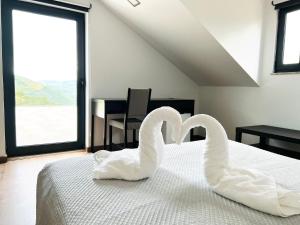 two swans sitting on a bed in a bedroom at Quinta da Pinguinha - Douro in Armamar