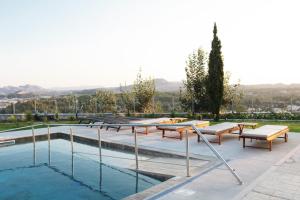 a pool with picnic tables and benches next to it at Maison A Rhodes with 66m2 heated pool on a 4800m2 plot in Koskinou