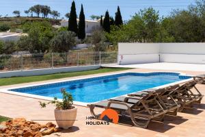 een zwembad met 2 ligstoelen en een zwembad bij #102 Villa Private Pool and Garden in Albufeira