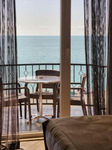 a balcony with a table and chairs and the ocean at Hotel Neptun Kvariati in Kvariati