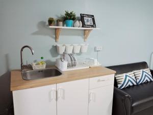 a kitchen counter with a sink and a couch at Nesto Condo at Muangthong in Pak Kret