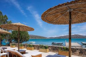 a view of the ocean from a resort with tables and umbrellas at Naiades Boutique Hotel - Adults Only in Elounda