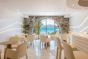 a restaurant with tables and chairs and a large window at Naiades Boutique Hotel - Adults Only in Elounda