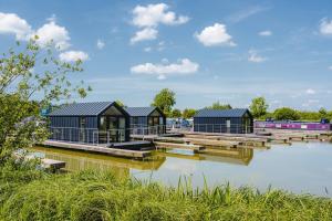 a row of houses on a dock on a body of water at Tattenhall Marina Floating Pods in Hargrave