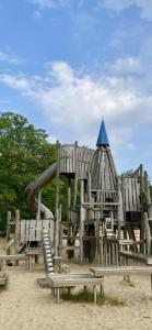 un parque infantil de madera con un tobogán en la arena en Haus Else, en Schüttorf