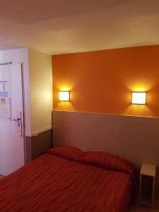 a bedroom with a bed and two lights on the wall at HECO Colmar Nord - ex Première Classe in Houssen