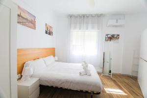 un dormitorio con una cama con un osito de peluche sentado en ella en RentalSevilla Disfruta por San Leandro en un alojamiento con 3 habitaciones en Sevilla