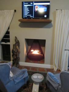 a living room with a fireplace with a tv on the wall at Omega Suite in Gansbaai