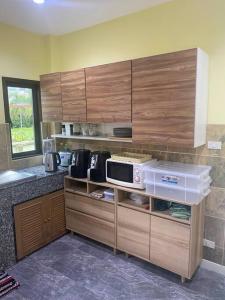 a kitchen with wooden cabinets and a microwave at Thai style 3 bedroom pool house. in Khao Lak